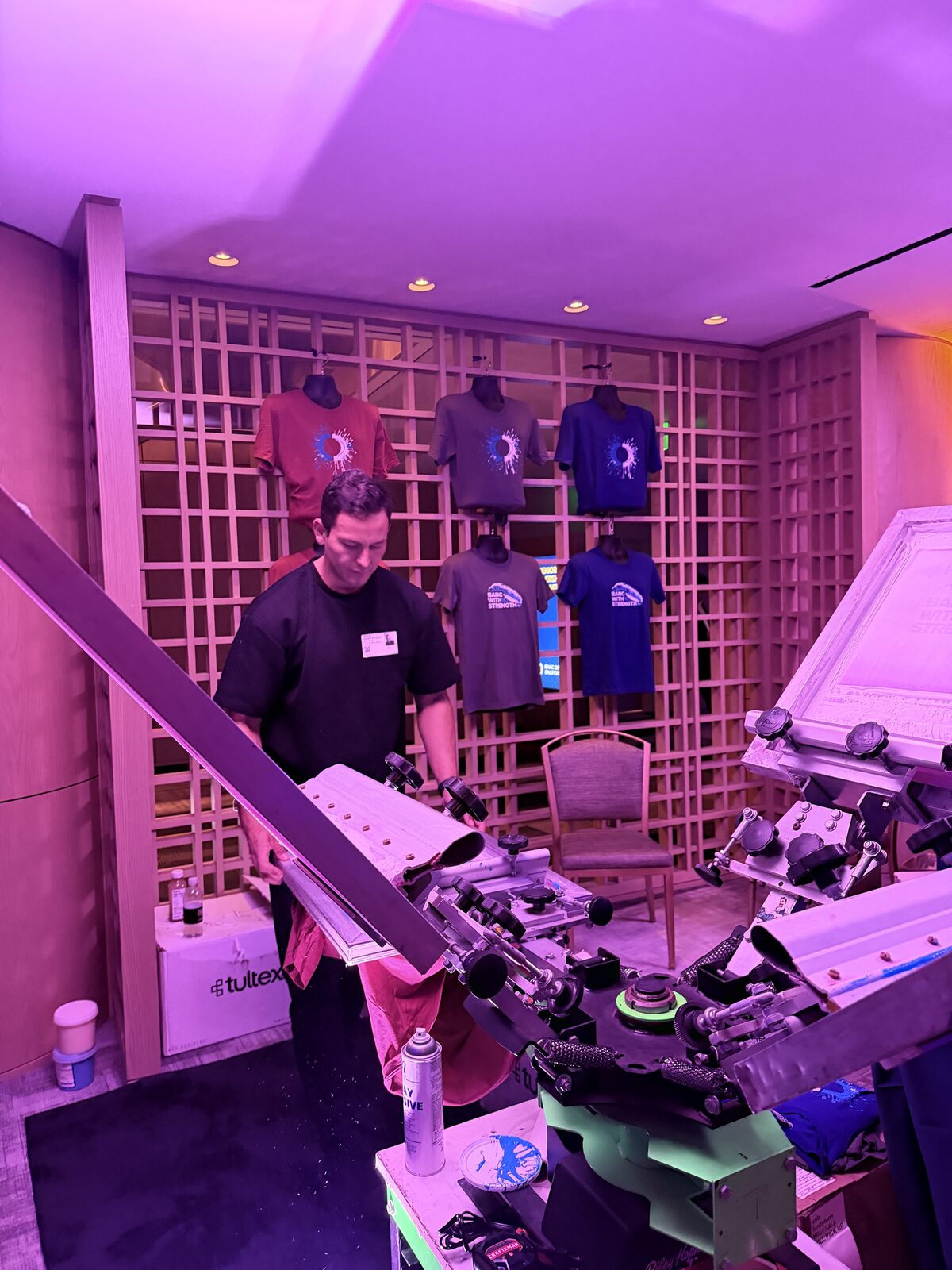Operator loading a blank shirt onto the press at a rented t-shirt bar