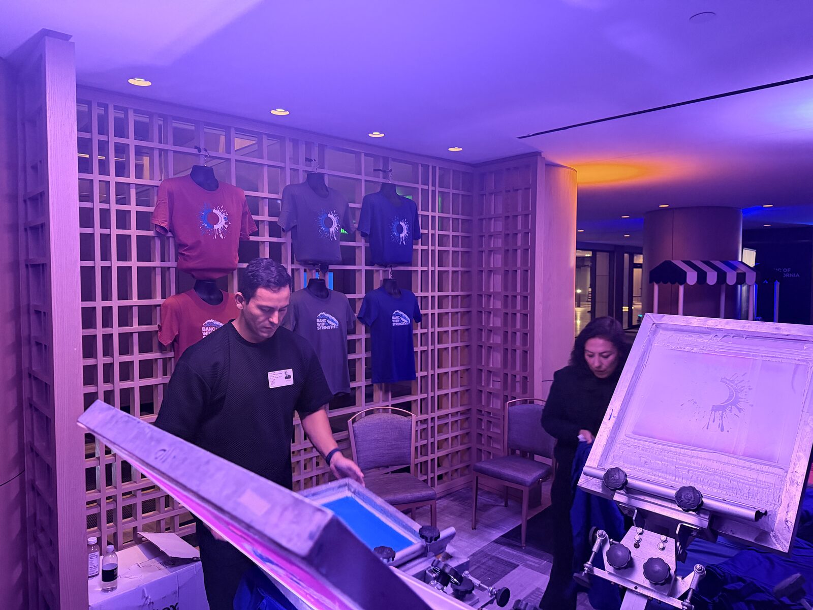 Wall of freshly printed event t-shirts on display at a t-shirt bar