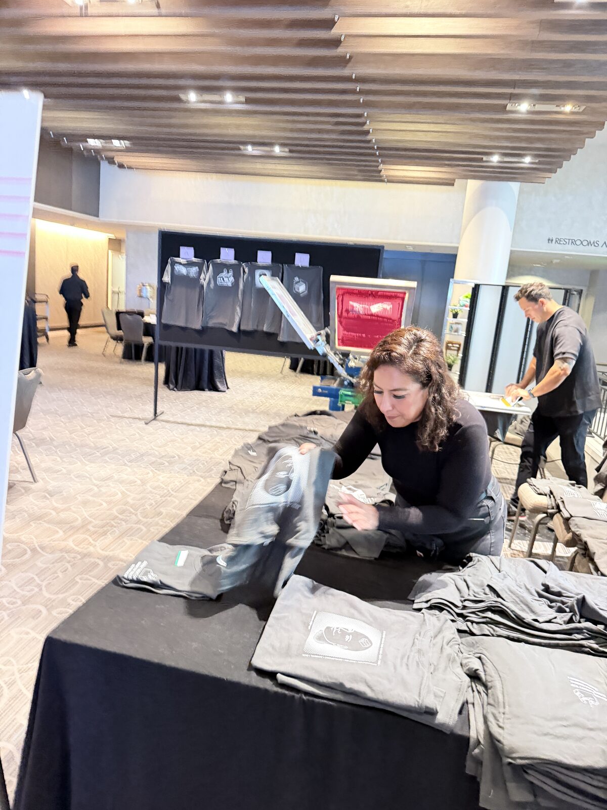 Crew folding fresh printed shirts at a t-shirt bar station